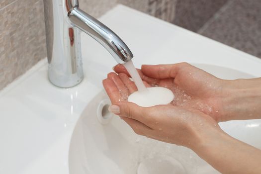 Washing of hands with soap under running water.