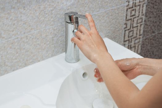 Washing of hands with soap under running water.