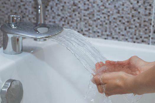 Washing of hands with soap under running water.