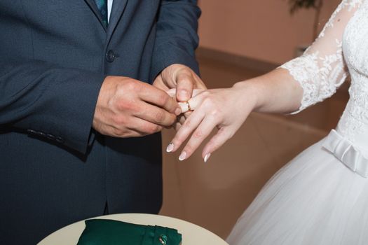 wedding rings and hands of bride and groom. young wedding couple at ceremony. matrimony. man and woman in love. two happy people celebrating becoming family.