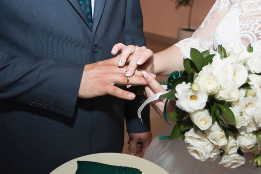 wedding rings and hands of bride and groom. young wedding couple at ceremony. matrimony. man and woman in love. two happy people celebrating becoming family.