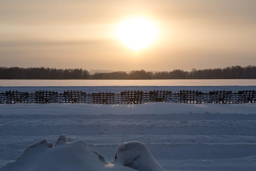 Sunset winter landscape with snow-covered road in yellow and dark colors