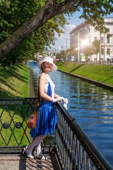 Young lady wearing white hat holding fan walking embankment