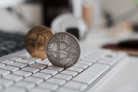 Digital currency physical metal bitcoin coin on the white keyboard near glass ball.