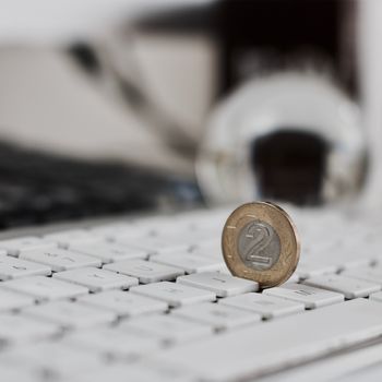 Physical coin polish money on the white computer keyboard.