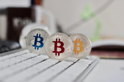 Digital currency physical metal bitcoin coin on the white keyboard near glass ball.