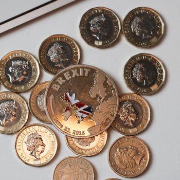 Europe leaving. Gold brexit coin with British map near keyboard and pound sterling.