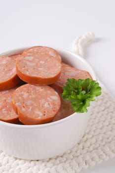 bowl of sliced pork sausage on white table mat