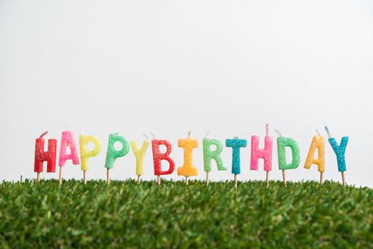 Birthday candles with grass on white background