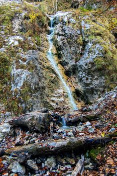 Small waterfall, stream flowing down through rocks and green moss, long exposure, Palenk waterfall in Logarska dolina, Logar valley, Slovenia