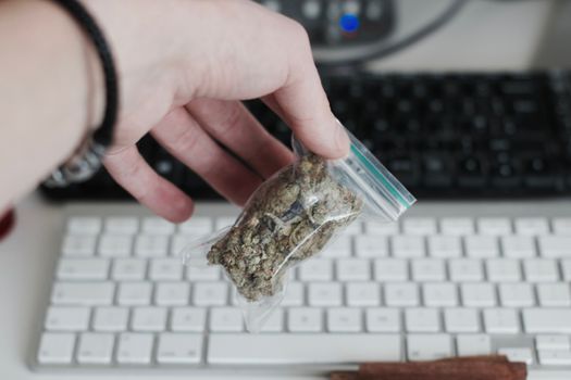 Green dry marijuana in man hand on the blurry background. Weed concept.