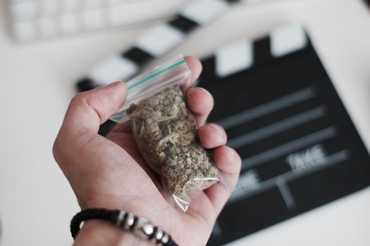 Green dry marijuana in man hand on the blurry background. Weed concept.