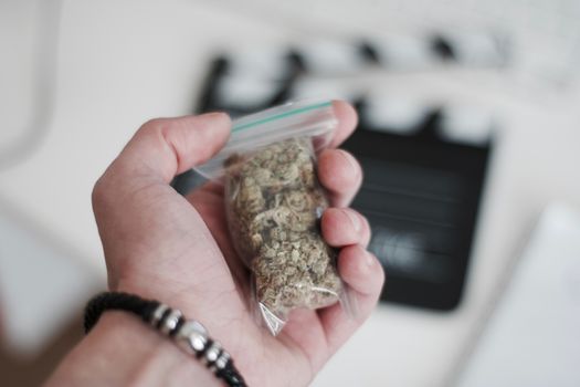 Green dry marijuana in man hand on the blurry background. Weed concept.