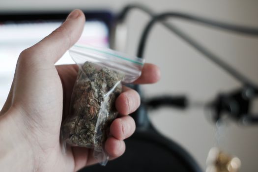 Green dry marijuana in man hand on the blurry background. Weed concept.