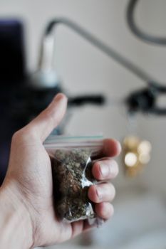 Green dry marijuana in man hand on the blurry background. Weed concept.