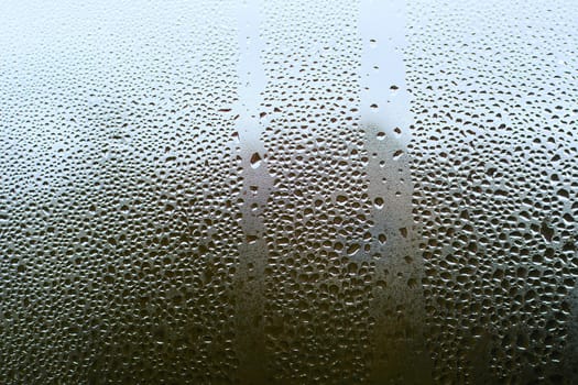 A view through dewy window with many small condensation drops.