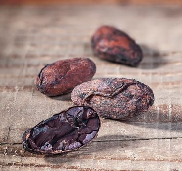Cocoa beans in a row with a blurry background. Cocoa beans on a rustic wooden table. Chopped cacao bean.