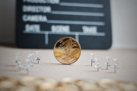 Digital currency physical gold feather coin. Cinema cryptocurrency concept.