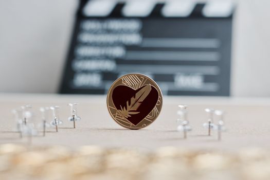 Digital currency physical gold feather coin. Cinema cryptocurrency concept.