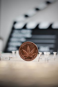 Brass marijuana coin in cinema concept. Legalize it, sativa.