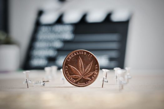 Brass marijuana coin in cinema concept. Legalize it, sativa.
