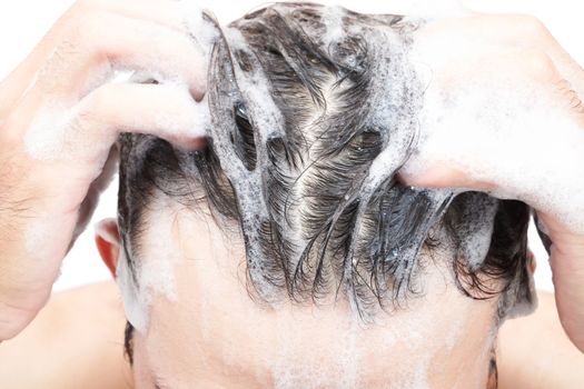 Closeup young man washing hair with white background, health care concept