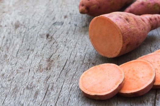 Sweet potato with slices on wooden background, raw food