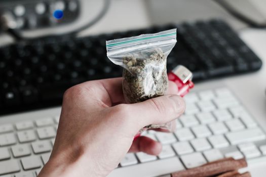 Green dry marijuana in man hand on the blurry background. Weed concept.