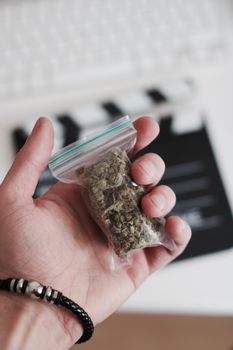 Green dry marijuana in man hand on the blurry background. Weed concept.