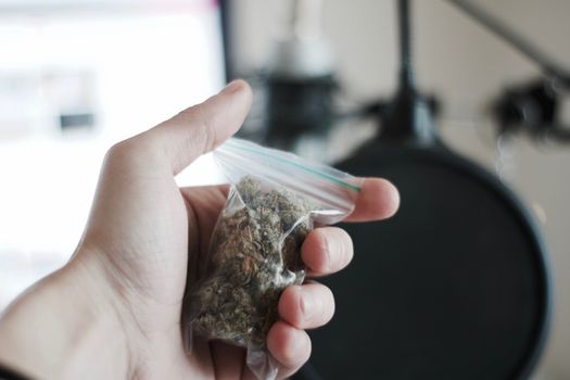 Green dry marijuana in man hand on the blurry background. Weed concept.