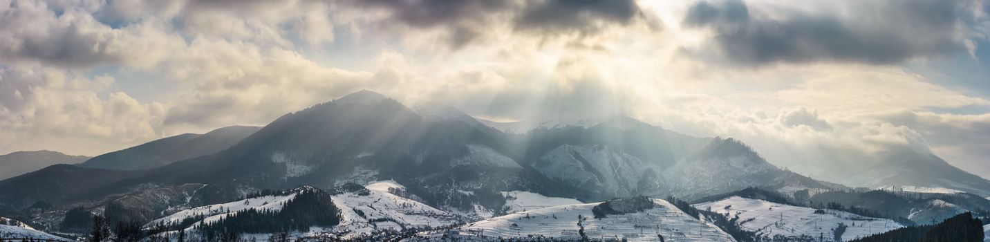 mountain ridge in light beams on cloudy winter day. gorgeous countryside panorama
