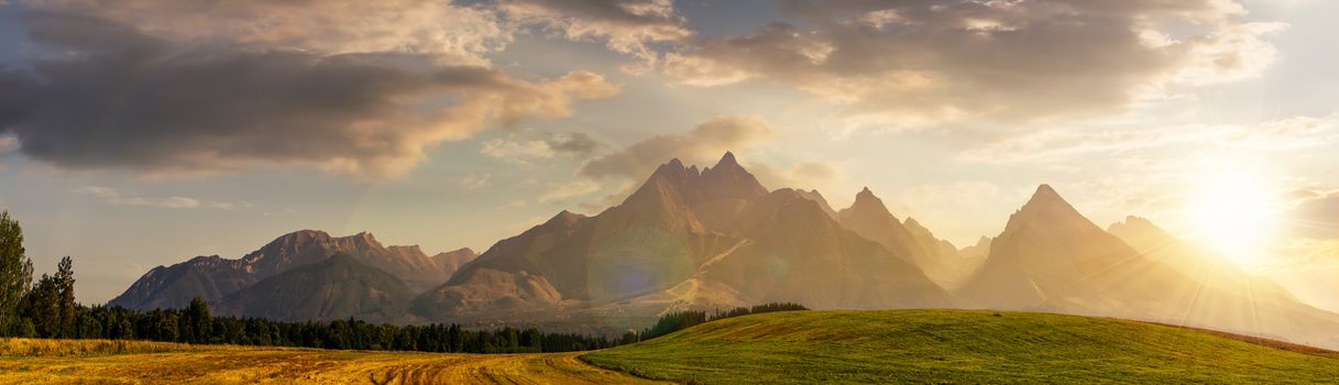 rural fields near Tatra Mountains in summer at sunset. beautiful panorama of agricultural area. gorgeous mountain ridge with high rocky peaks
