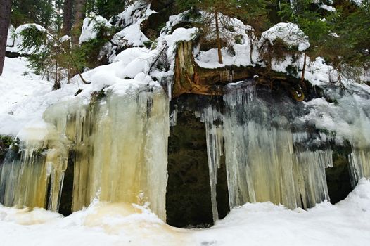 Frozen waterfalls on the rock, orange colored and snow