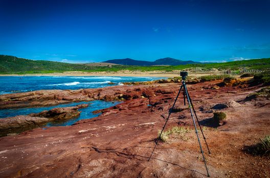 Compact camera on tripod shooting at the coast in a sunny windy day