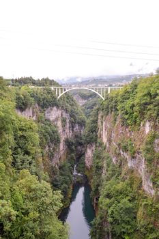 Bridge with an arch between two rock walls and over a river in the dolomites in Italy