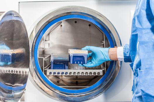 Scientist sterilizing laboratory material in autoclave