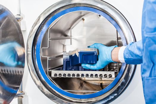 Scientist sterilizing laboratory material in autoclave