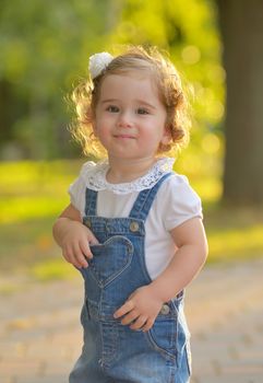 Happy little girl in autumn park against sun