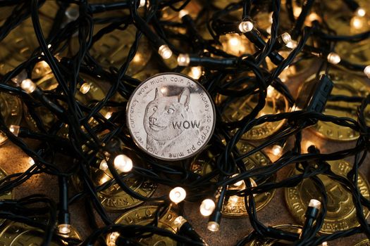 Digital currency physical brass dogecoin coin. Christmas light cryptocurrency concept.