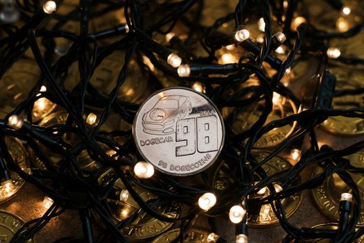 Digital currency physical brass dogecoin coin. Christmas light cryptocurrency concept.