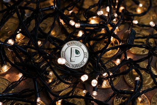 Digital currency physical small gold peercoin coin. Christmas light concept.