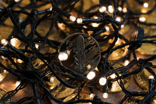 Digital currency physical metal gold feather coin near the light. Christmas cryptocurrency concept.