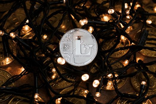 Digital currency physical metal Litecoin coin on the christmas lights concept.
