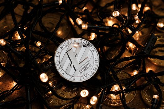 Digital currency physical metal Litecoin coin on the christmas lights concept.