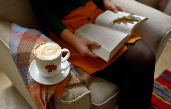 Cup of cappuccino coffee and girl reading a book