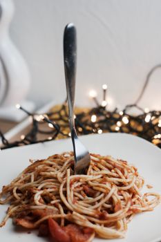 Italian tasty pasta with tomatoes on a fork. Christmas food concept.