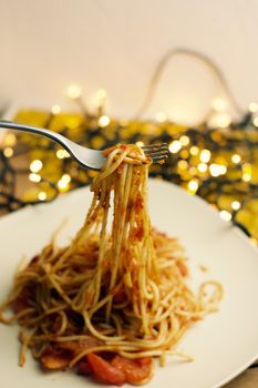 Italian tasty pasta with tomatoes on a fork. Christmas food concept.