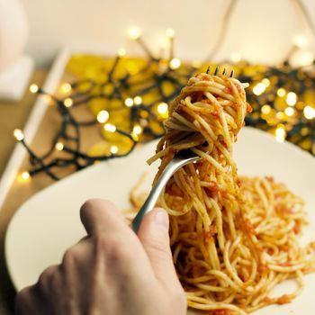 Italian tasty pasta with tomatoes on a fork. Christmas food concept.