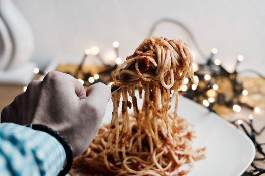 Italian tasty pasta with tomatoes on a fork. Christmas food concept.