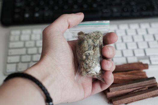 Green dry marijuana in man hand on the blurry background. Weed concept.